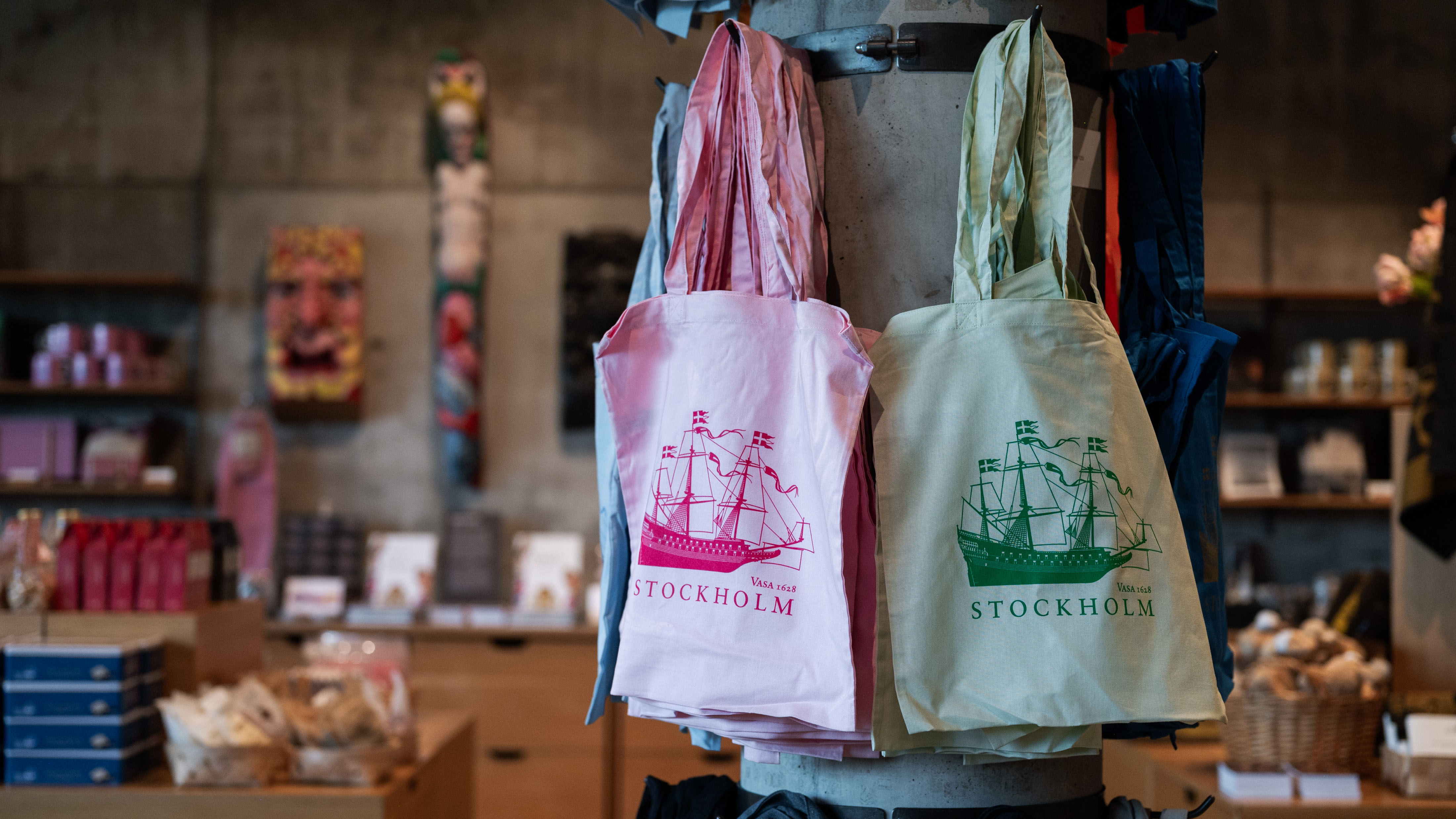 Tygpåsar i olika färger med motiv av skeppet Vasa och texten ”Stockholm” hänger på en pelare i museibutiken.