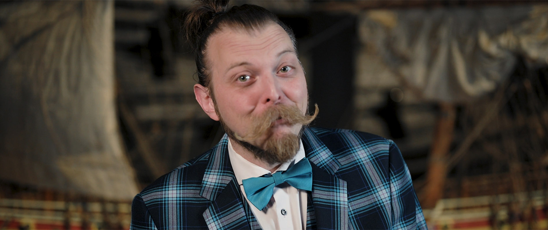 Trollkarlen Stefan Eriksson med mustasch pch hästsavns syns framför en modell av skeppet Vasa. 