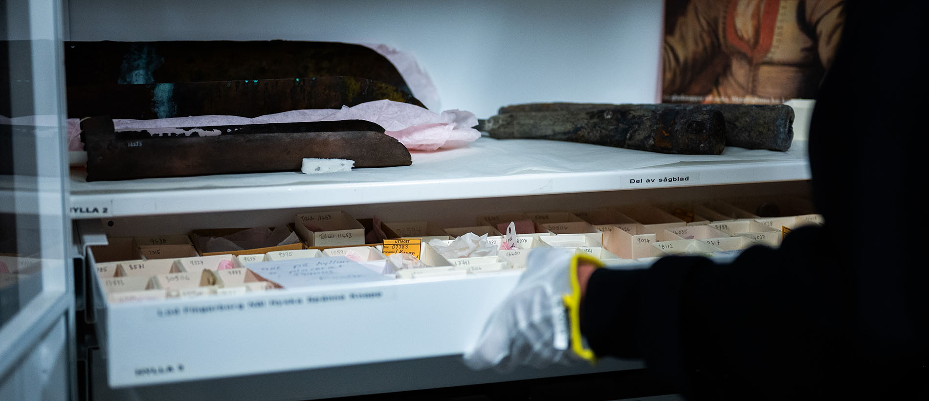 Person med vita handskar tar ut föremål ur arkivskåp