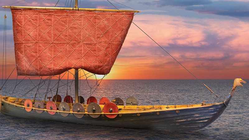 Bild av vikigaskepp med orange segel och sköldar över relingen. 