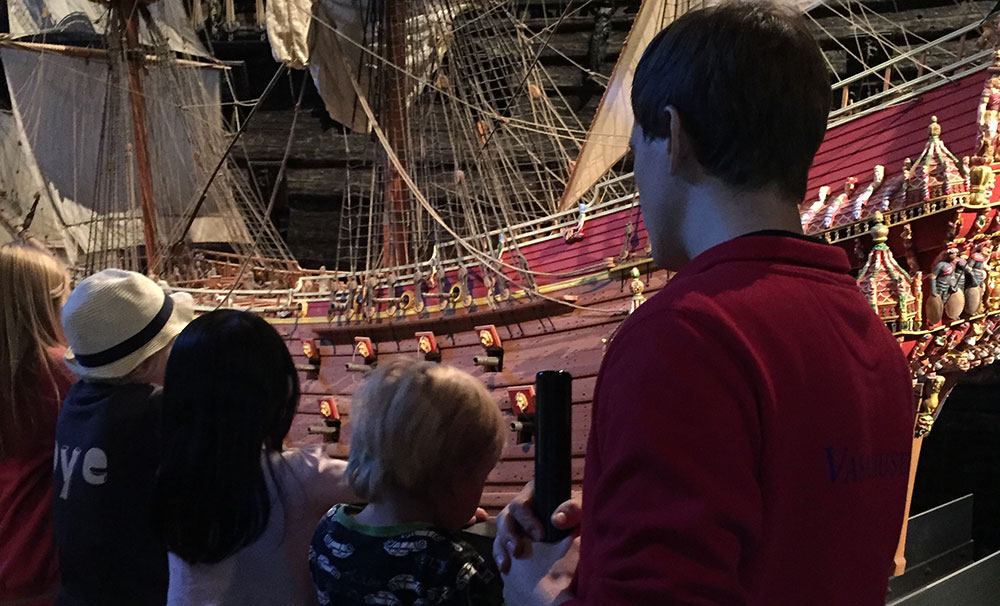Fyra bar står tillsammans med en av museets guider och tittar på tiondelsmodellen som finns utställd i museet.