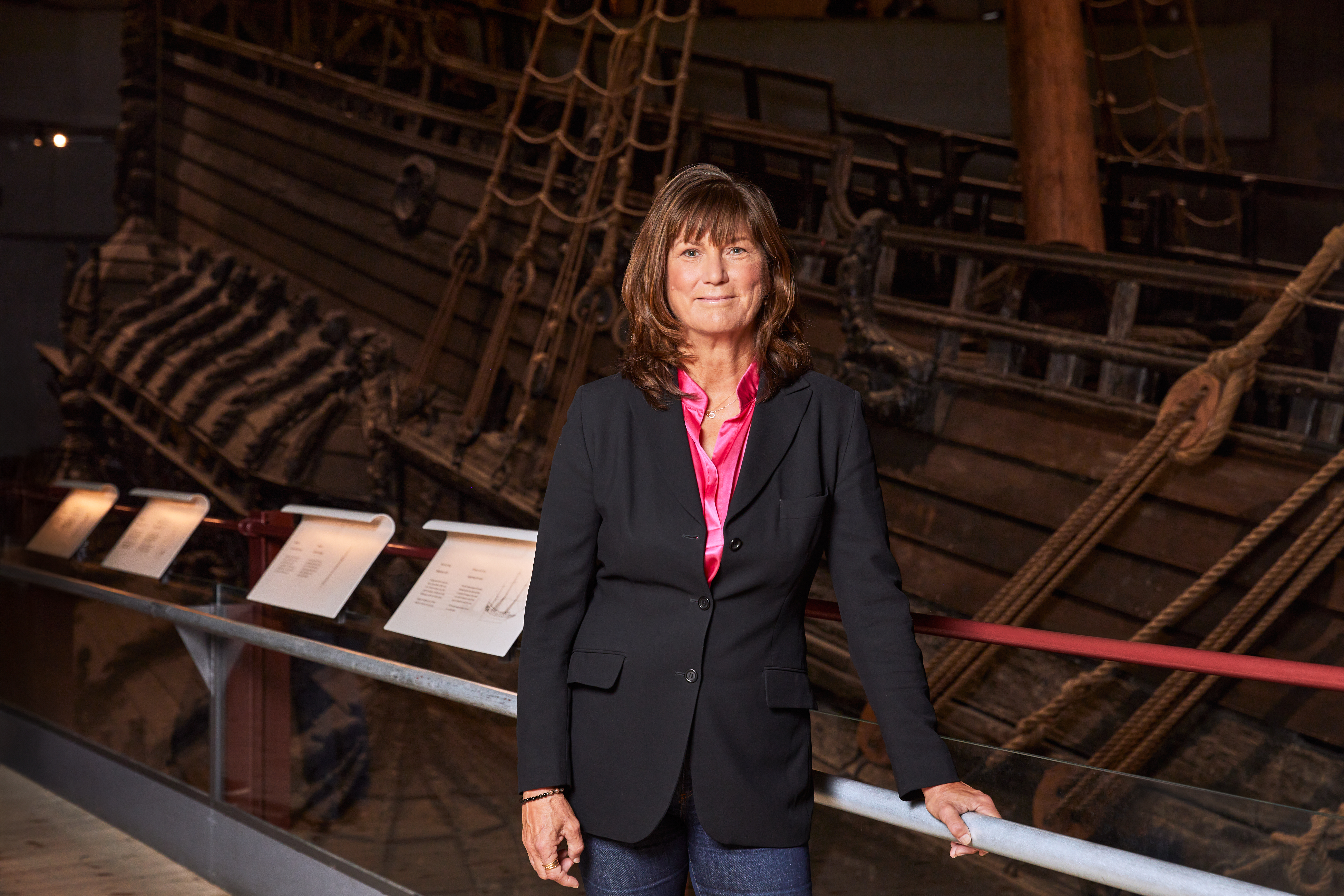 Kvinna med brunt hår och kavaj framför skeppet Vasa.